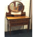 An Edwardian mahogany boxwood strung dressing table, with oval mirror on scrolled supports above a