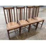 A set of four oak dining chairs with lathe backs and drop-in upholstered seats, raised on square