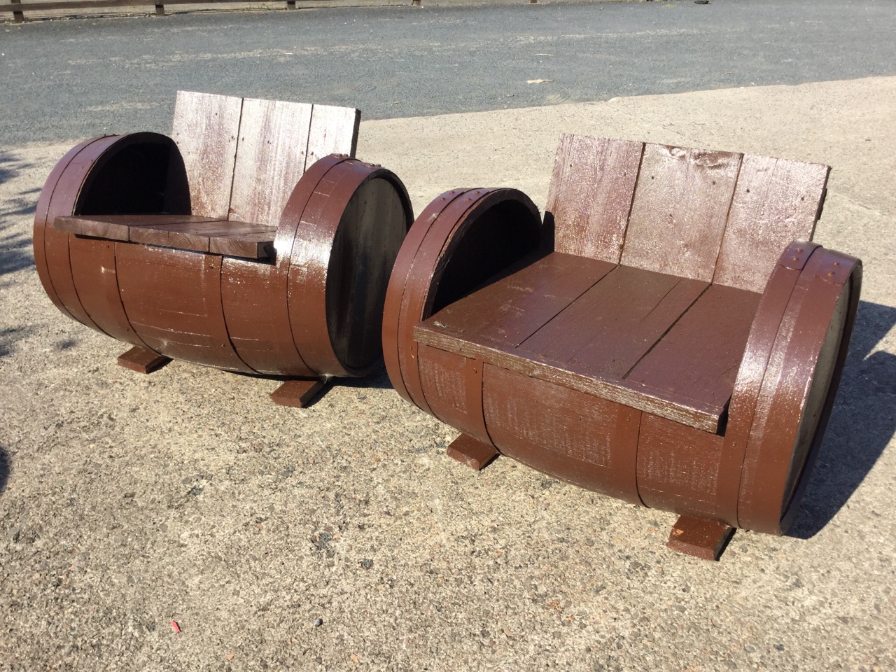 A pair of painted garden seats formed out of old barrels, with boarded backs and seats cut into