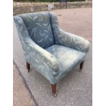 A late Victorian mahogany wing armchair, the padded back above a sprung seat, raised on square
