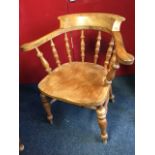 A mahogany captains chair, the shaped bow back on spindles above a solid seat, raised on turned legs