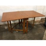 A 70s teak drop-leaf dining table with pierced rectangular supports, each end with two gates. (