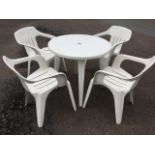 A circular garden dining table with four chairs, the top with hole for shade, raised on angled