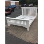 A modern double bed, having slatted headboard & tailboard beneath moulded platforms, with square