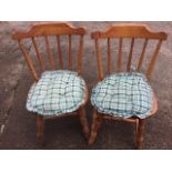 A pair of pine spindleback chairs, the rounded seats with button upholstered cushions, raised on