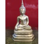 A heavy cast brass seated Buddha, the deity with noduled hair beneath scrolled finial, seated