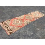 A Turkey runner woven with three floral medallions on pink field with conforming halved and