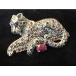 A silver ruby and marcasite brooch modelled as a panther, the beast lying above an oval claw set