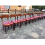 A set of twelve George IV mahogany dining chairs with wide arched back rails on leaf carved scrolled