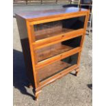 A walnut bookcase with crossbanded top above three shelves with up-and-over glass doors, having