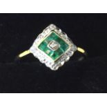 A cased deco style 9ct gold ring with square panel of emeralds framing a single brilliant cut