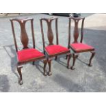 A set of three Queen Anne style mahogany dining chairs with shaped backs above vase splats, having