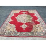 A large oriental style carpet woven with star medallion with pendants on red field, within a wide