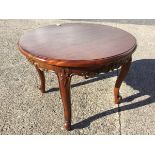 A circular mahogany coffee table with foliate scroll carved frieze on tapering scrolled supports. (