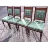 A set of four Edwardian mahogany dining chairs with moulded backs framing upholstered panels, the