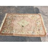 An oriental chenille style rug woven with scalloped medallion on pink field - holed. (67in x 48.