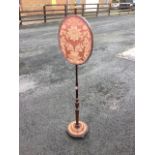 A nineteenth century mahogany pole screen with oval damask panel on turned column surmounted by