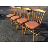 A set of four Polish beech spindleback kitchen chairs with waved back rails on turned spindles,