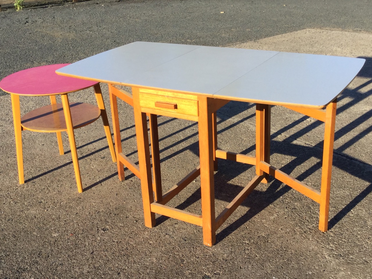 A circular formica topped table on angled rectangular tapering legs joined by platform stretcher;