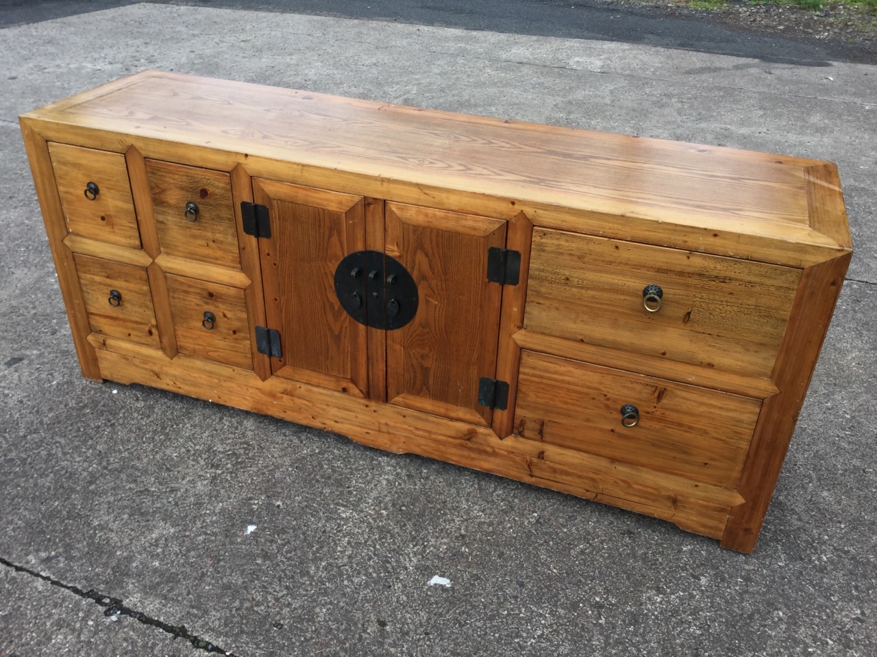 An oriental style sideboard with panelled top above central two-door cupboard mounted with