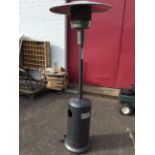 A gas patio heater with gauze reflector on column above a tubular base on casters, complete with a