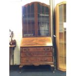 A Queen Anne style walnut bureau bookcase, the arched top with astragal glazed doors enclosing