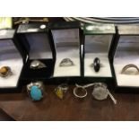 Nine miscellaneous silver rings - a heavy band, polished stones, a tigers eye framed by beaded