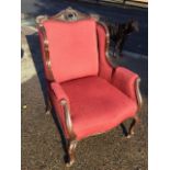 A late Victorian mahogany wing armchair with pierced scroll carved back rail and moulded arms