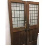 A pair of Victorian oak vestibule doors with leaded glass windows above twin moulded panels, each