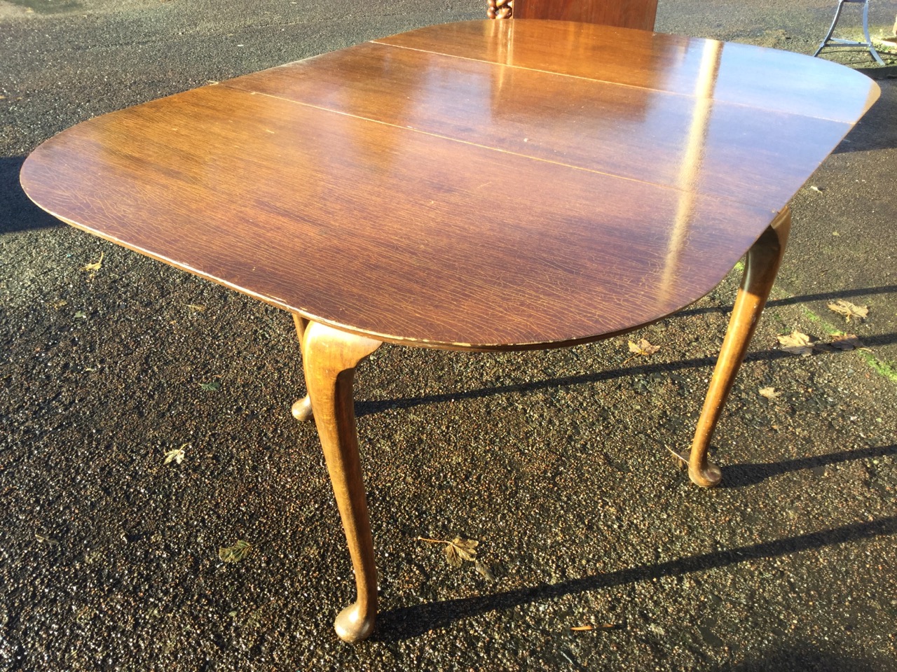 A rectangular rounded dining table, the top with drop-leaves raised on cabriole gate legs with pad