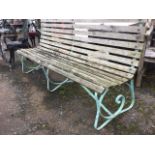 An Edwardian garden bench with scrolled wrought iron frame on three supports, having slatted
