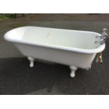 A Victorian cast iron roll-top bath with shaped feet, fitted with a pair of chrome taps with hot &
