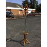 A bentwood coatstand with six scrolled hooks on column, with waisted legs joined by a ring forming a