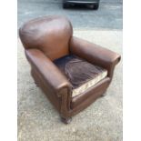 A leather upholstered armchair with rounded back and scroll shaped arms with brass studding,