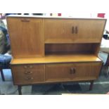 A mid-century teak dresser with panelled doors and drop-down compartment above an open shelf, the
