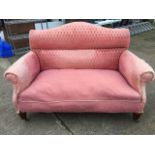 An Edwardian mahogany sofa with arched padded back above a sprung seat with scrolled arms, raised on