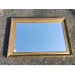 A rectangular mirror in press moulded gilt frame. (22.5in x 31.5in)