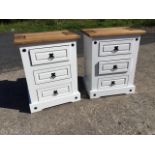 A pair of bedside cabinets with grooved tops above white painted towers each with three panelled