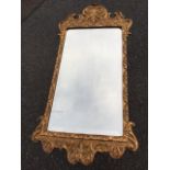 A George II style gilt wall mirror, with rectangular rounded bevelled plate in leaf moulded gesso