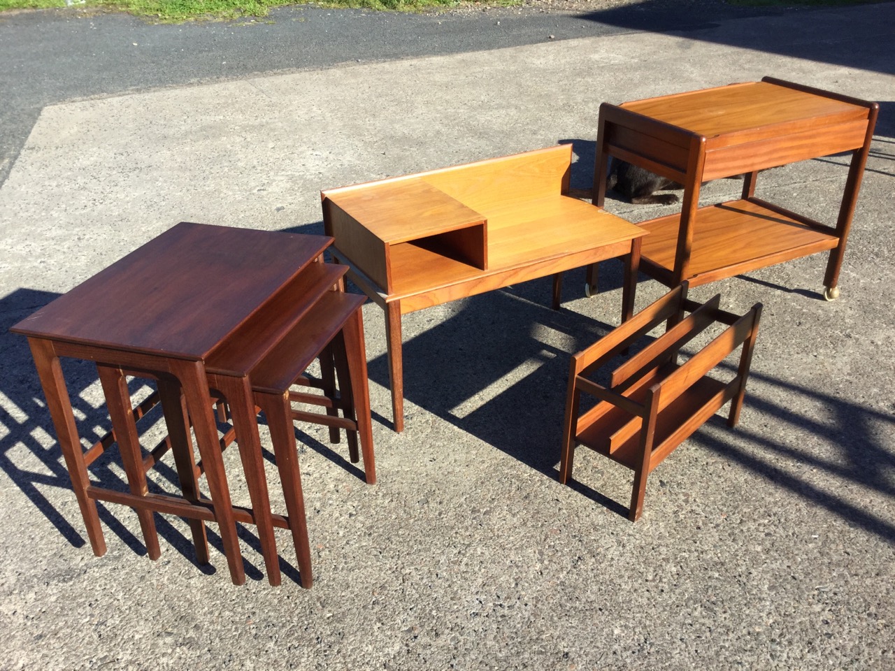 A teak trolley with tray platforms and a drawer; a teak telephone table or bench raised on square