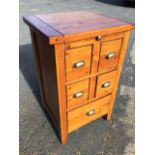 A small pine cabinet with cleated top above a slide, having four small drawers mounted with brass