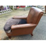 A leather upholstered armchair with long rounded sprung seat and padded arms, having later loose