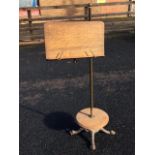 A Victorian oak music stand with brass column on cast iron paw feet, mounted with adjustable arm