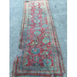 An antique Turkey runner woven with blue/green floral motifs in red field framed by linked borders