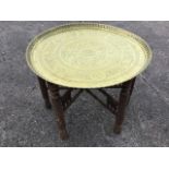 A circular brass tray-top coffee table having Islamic decoration within a fluted rim, supported on