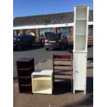 A tall white cabinet having open compartment with shelves above a door; two mahogany style bookcases