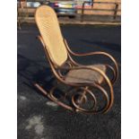 An Edwardian Fischel bentwood rocking chair, with cane back & seat on scrolled frame with shaped