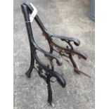A pair of cast iron bench ends with scrolled decoration on channelled sabre legs. (2)