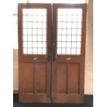 A pair of Victorian oak vestibule doors with leaded glass windows above twin moulded panels, each