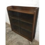 A 50s walnut bookcase with sliding glass doors enclosing shelves, raised on plinth. (35.5in x 9in